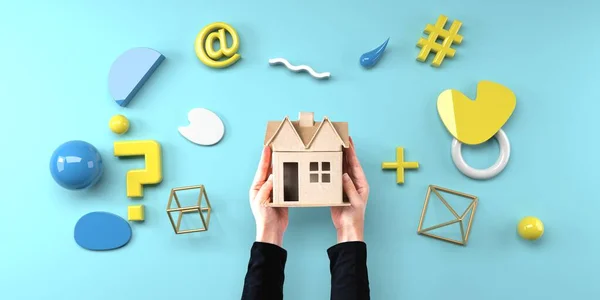 Person holding a cardboard house with geometric shapes from above