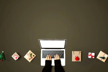 Yukarıdan hediye kutuları olan bir dizüstü bilgisayar kullanan kişi