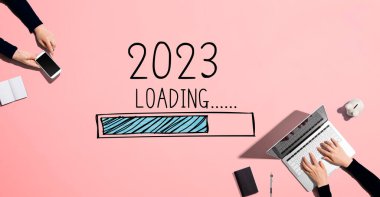2023 yılını dizüstü bilgisayar ve telefonla çalışan insanlarla yükleme