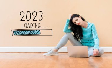 Yeni yıl 2023 'ü dizüstü bilgisayar kullanan genç bir kadınla dolduruyorum.
