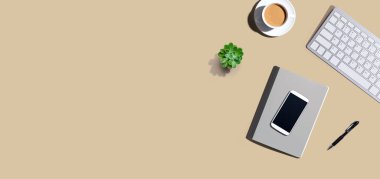 Masa ögeleri - klavye, akıllı telefon, kahve ve yukarıdan bir kalem.