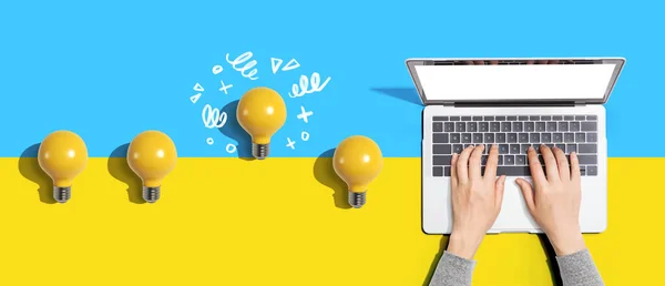 Idea light bulbs with person using a laptop computer from above