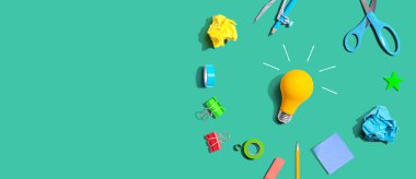 Idea light bulb with school supplies overhead view - flat lay