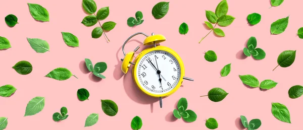 緑の葉と黄色のヴィンテージ目覚まし時計 フラットレイ — ストック写真