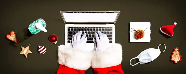 Der Weihnachtsmann Mit Einem Laptop Mit Maske Und Einer Desinfektionsflasche Stockfoto