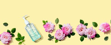 Üstünde pembe güller olan dezenfektan şişesi düz yerde.