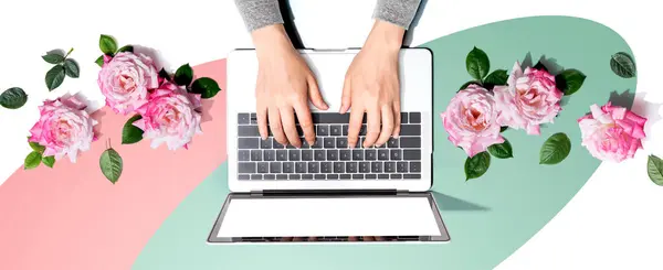 Vrouw Met Behulp Van Haar Laptop Met Roze Rozen Platte Stockfoto