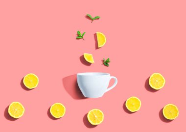Fresh yellow lemons with tea cup overhead view - flat lay clipart