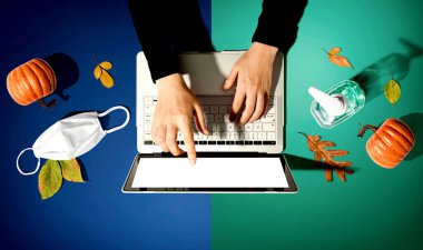 Sonbaharda bir dizüstü bilgisayar, maske ve dezenfektan kullanan kişi.