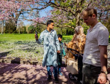 Danimarka 'nın Kopenhag kentindeki Bispegjerg mezarlığında kiraz ağacı bahar çiçeklerini ziyaret eden Asyalı bir aile.