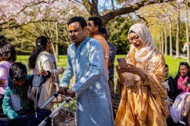 Danimarka 'nın Kopenhag kentindeki Bispegjerg mezarlığında kiraz ağacı bahar çiçeklerini ziyaret eden Asyalı bir aile.