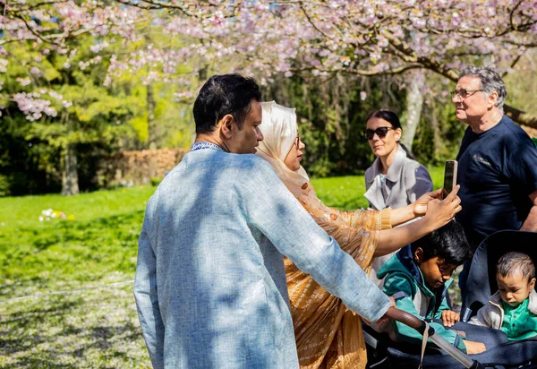 stock image Asian family taking selfie at the cherry tree spring blossom at Bispegjerg cemetery in Copenhagen, Denmark