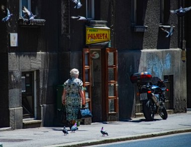THESSALONIKI, GREECE, 13 HAZİRAN 2010: Kuşlarla çevrili sokakta yürüyen bir bayan. Fotoğraf Zagreb, Hırvatistan 'da 2010 yılında çekildi.
