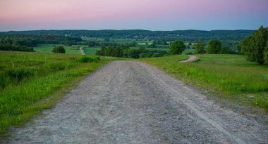 İsveç, Hassleholm 'deki Hovdala Hills' te çakıllı yolda gün batımı.