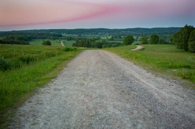 İsveç, Hassleholm 'deki Hovdala Hills' te çakıllı yolda gün batımı.