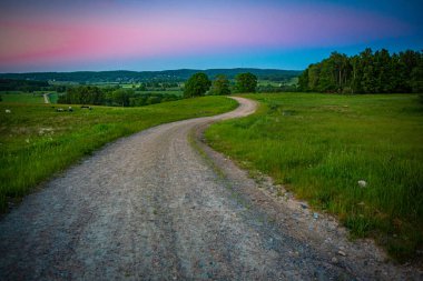 İsveç, Hassleholm 'deki Hovdala Hills' te çakıllı yolda gün batımı.