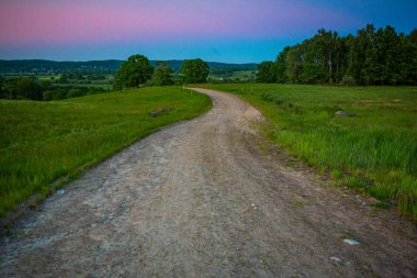 İsveç, Hassleholm 'deki Hovdala Hills' te çakıllı yolda gün batımı.
