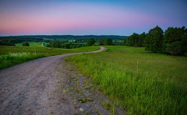 İsveç, Hassleholm 'deki Hovdala Hills' te çakıllı yolda gün batımı.