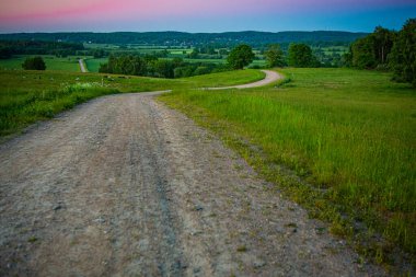 İsveç, Hassleholm 'deki Hovdala Hills' te çakıllı yolda gün batımı.
