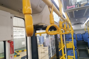 İçinde sıralı koltuklar, kapı kolları ve ekran bulunan modern bir kamu otobüsünün içi. Günlük banliyö ve şehir seyahatleri için hazır..