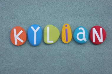 Kylian, elle boyanmış yeşil kumların üzerine çok renkli taş harflerle yazılmış erkeksi bir isim.