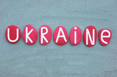 Ukraine, country name composed with red colored stone letters over green sand