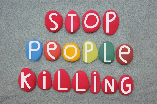 Stop people killing, social and creative message composed with multi colored stone letters over green sand