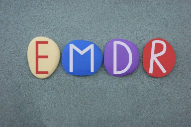 EMDR, Göz Hareketi Duyarsızlaştırma ve Yeniden İşleme, yeşil kum üzerinde çok renkli taş harflerle oluşturulmuş yaratıcı metin