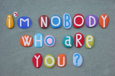 Ben hiçkimseyim, sen kimsin? Yeşil kumların üzerinde çok renkli taş harflerle oluşturulmuş yaratıcı yaşam tarzı sorusu.