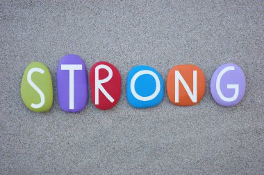 Sahildeki kumların üzerinde çok renkli taş harflerle oluşturulmuş güçlü, yaratıcı bir kelime.