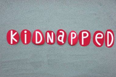 Kaçırılan metin, yeşil kumların üzerine elle boyanmış kırmızı renkli taş harflerle yazılmış.