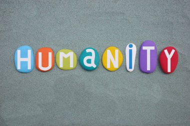 Humanity, social slogan composed with multi colored stone letters over green sand clipart