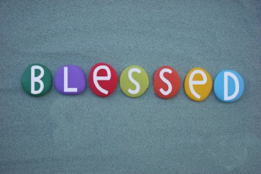 Kutsanmış kelime yeşil kumların üzerinde çok renkli taş harflerle oluşturulmuş.