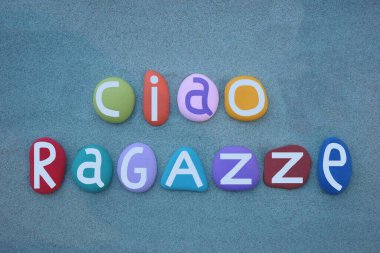 Ciao ragazze, merhaba kızlar, İtalyan dilinde yazılmış çok renkli taş harflerle yeşil kum üzerine yazılmış yaratıcı bir mesaj.