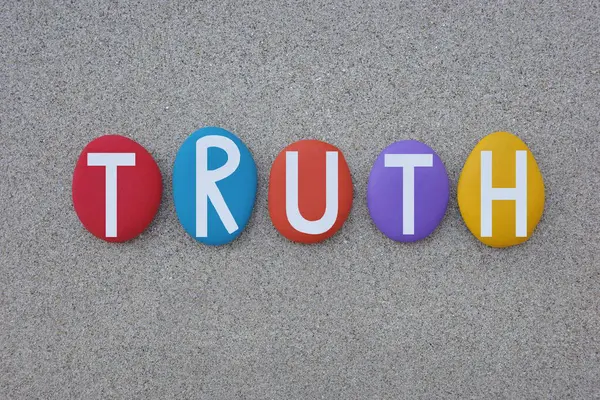 Gerçek, gerçek olma durumu, kumsaldaki kumların üzerine çok renkli taş harflerle yazılmış yaratıcı metin.