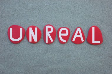 Gerçek dışı, İngilizce kelime yeşil kumların üzerine elle boyanmış kırmızı taştan harfler.