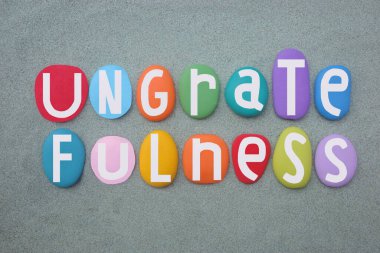 Nankörlük, minnettarlık göstermemek, yeşil kumların üzerine çok renkli taş harflerle yazılmış yaratıcı bir metin.