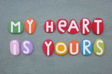 Kalbim senindir, yeşil kumların üzerine çok renkli taş harflerle yazılmış yaratıcı aşk mesajı.