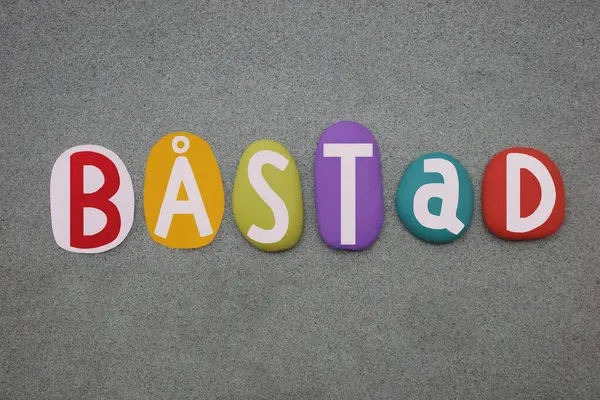 Stock image Bastad, seat of Bastad Municipality, Scania County, Sweden, souvenir composed with hand painted multi colored stone letters over green sand