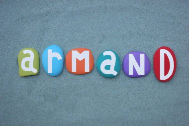 Armand, erkeksi bir isim. Elle boyanmış yeşil kumların üzerine çok renkli taş harfler.