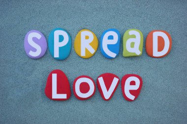 Aşkı yaymak, sosyal slogan, el yazısı ile bestelenmiş, yeşil kumların üzerine çok renkli taş harfler.