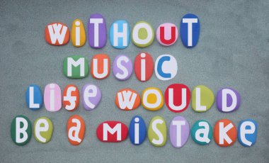 Müzik olmadan, hayat bir hata olurdu, Alman filozof Friedrich Nietzsche 'nin yeşil kumların üzerine elle boyanmış çok renkli taş harfler.