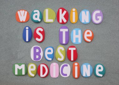 Yürümek en iyi ilaçtır. Sağlıklı ve sosyal slogan, yeşil kumların üzerine çok renkli taş harflerle yazılmış.