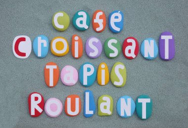 Kafe, kruvasan, tapis roulant, yaratıcı Fransız sloganı çok renkli taş harflerle yeşil kumların üzerine boyanmış.