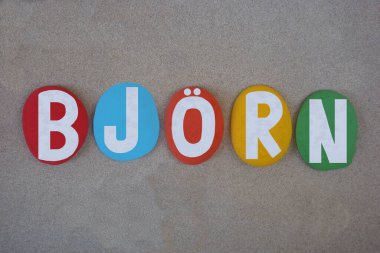 Bjorn, İskandinav kökenli erkeksi bir isim, yani eski İskandinav ayısı, kumsalda kumların üzerine çok renkli taş harflerle yazılmış yaratıcı kompozisyon.