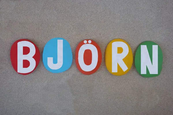 Bjorn, İskandinav kökenli erkeksi bir isim, yani eski İskandinav ayısı, kumsalda kumların üzerine çok renkli taş harflerle yazılmış yaratıcı kompozisyon.