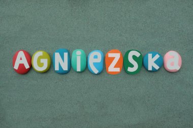 Agniezska, cilalı kadın ismi. Çok renkli el yazısıyla yeşil kumların üzerine taş harfler çizilmiş.