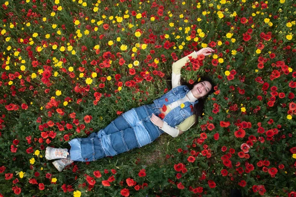 赤いケシの花の分野に眠っている若い幸せな女の子 春の女性のドローン航空 — ストック写真