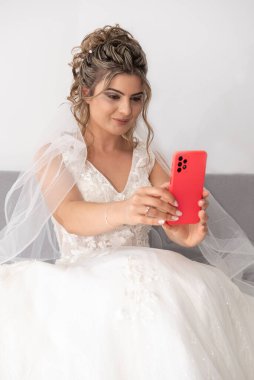 Güzel gelin kırmızı cep telefonuyla kendi portresini çekiyor.