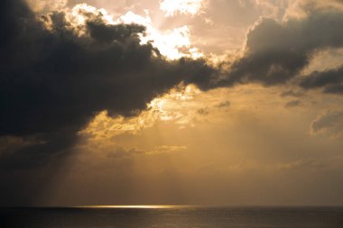 Bulutlu bulutlar ve turuncu renklerle denizde gün doğumu. Sabahleyin deniz manzarası. Okyanusta güneş ışınları
